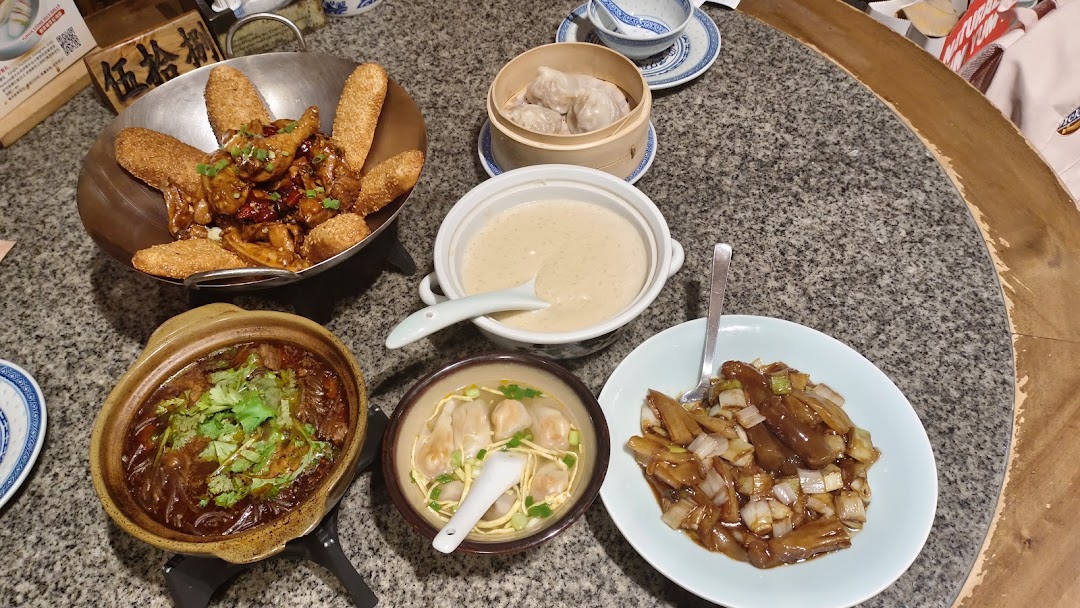 A table filled with a variety of delicious Chinese dishes, including dumplings, stew, and stir-fries.