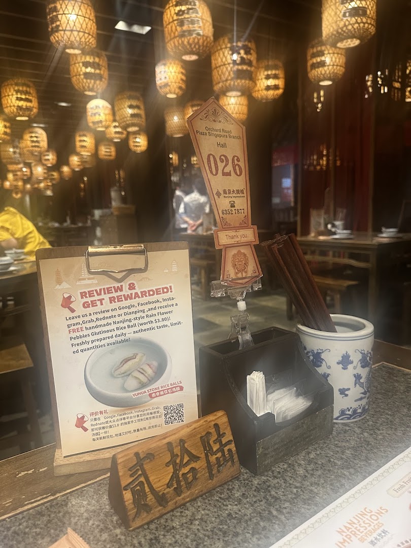 An interior shot of Nanjing Impressions restaurant, featuring a table setting, review promotion, and traditional lanterns.