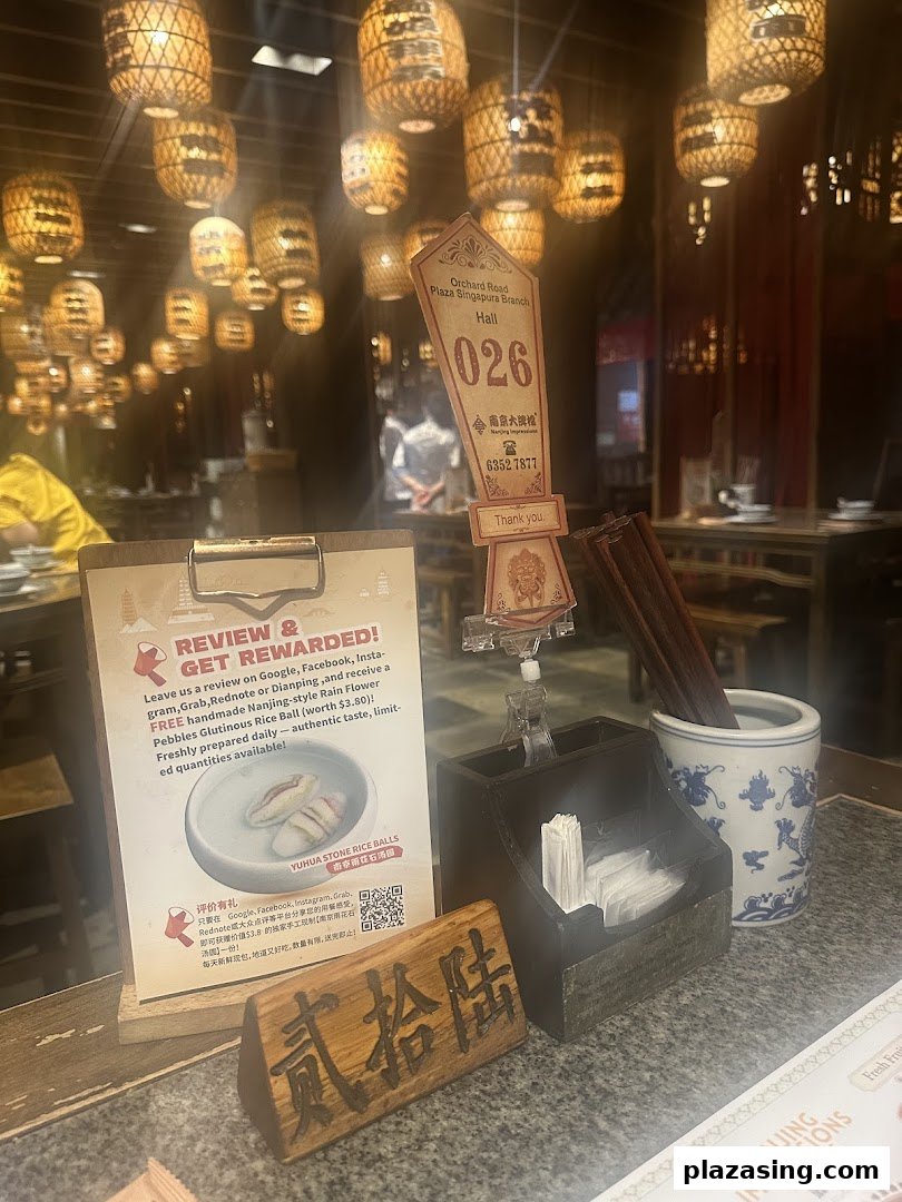 An interior shot of Nanjing Impressions restaurant, featuring a table setting, review promotion, and traditional lanterns.