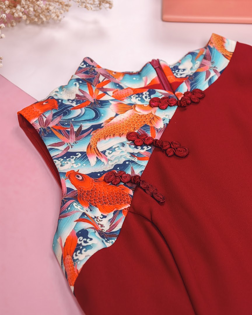 Close-up of a red dress featuring a vibrant koi fish pattern and traditional frog closures.