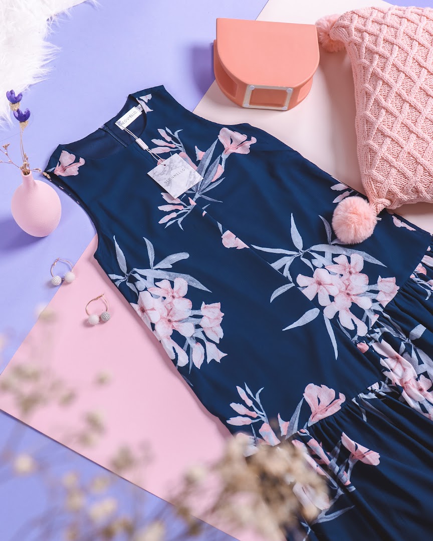 A stylish navy blue floral dress displayed with complementary accessories on a vibrant, multi-colored background.