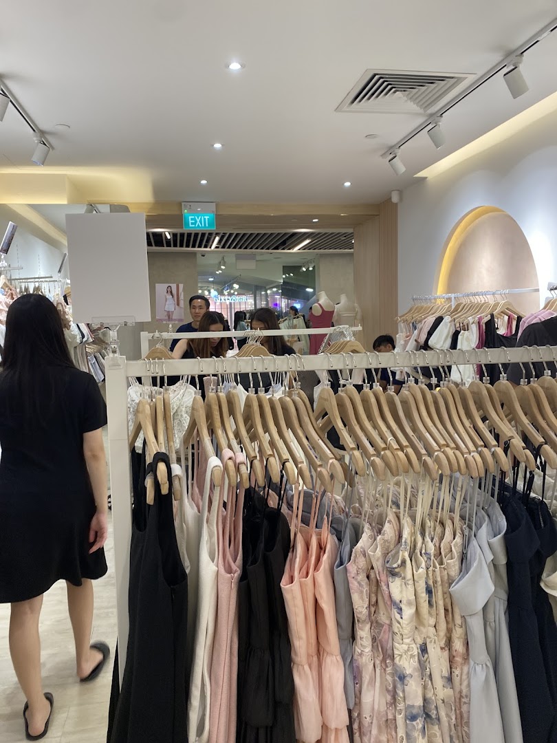 Interior of a clothing store, showcasing racks of dresses and customers browsing.