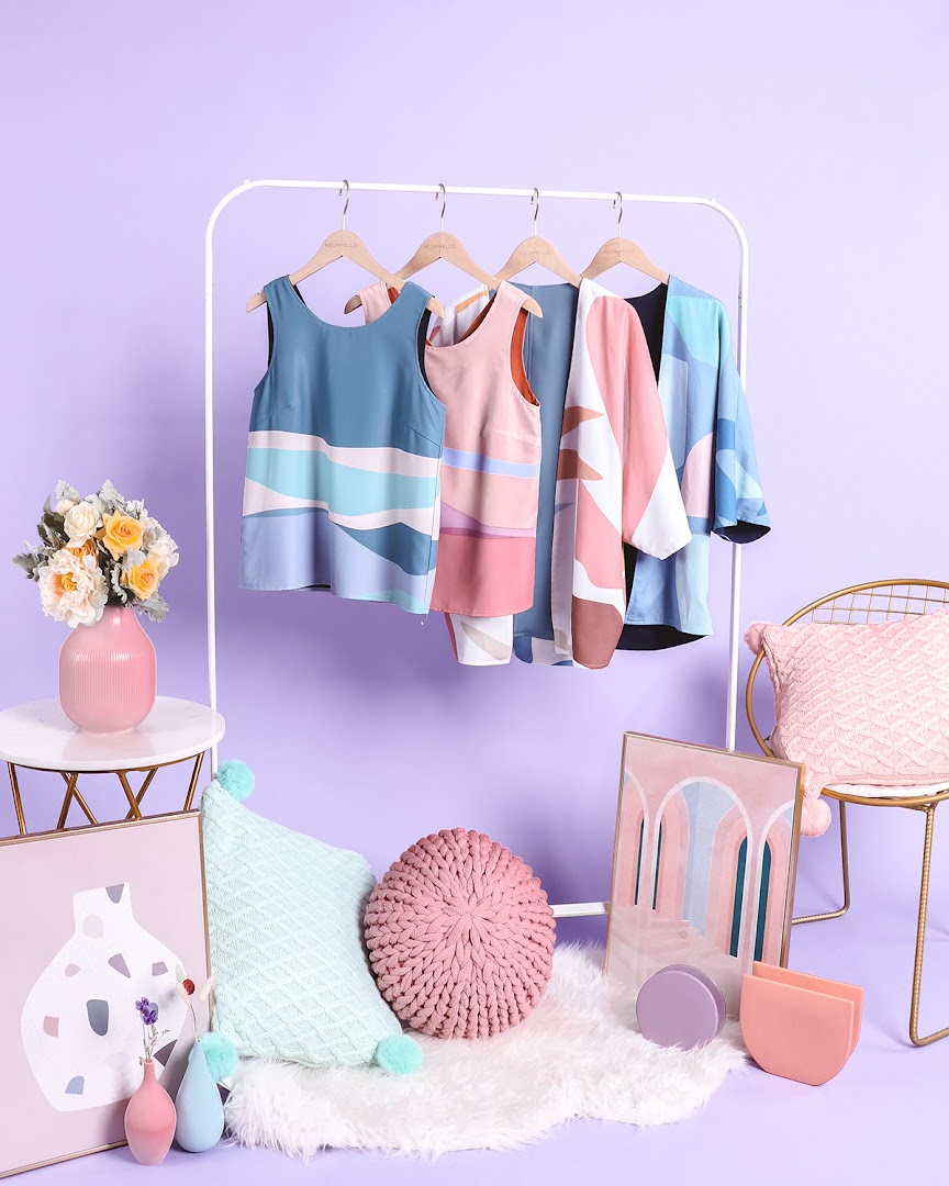 Vibrant patterned clothing on a rack, surrounded by stylish home decor items against a lavender backdrop.