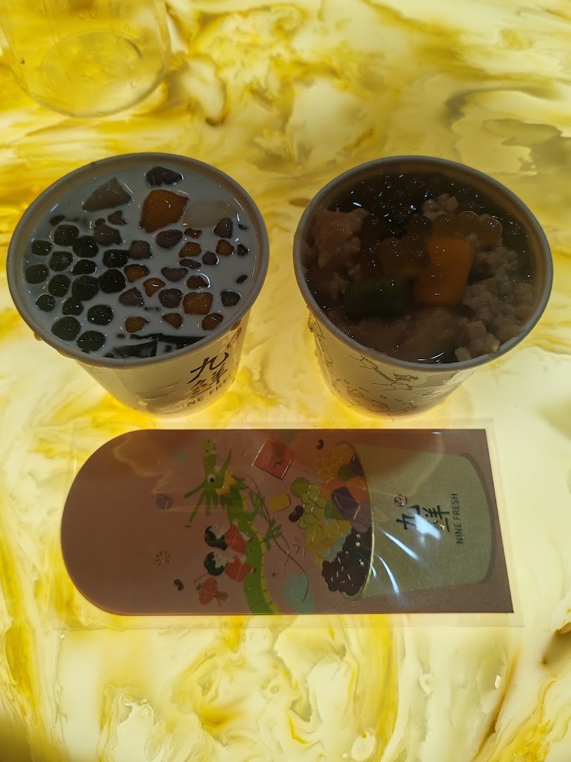 Two cups of Nine Fresh Taiwanese desserts with various toppings and a promotional card on a yellow surface.