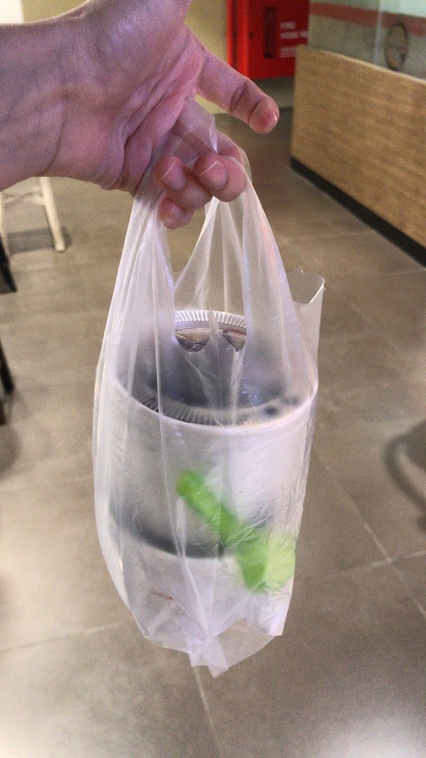A hand holds a plastic bag containing a takeaway dessert from Nine Fresh.