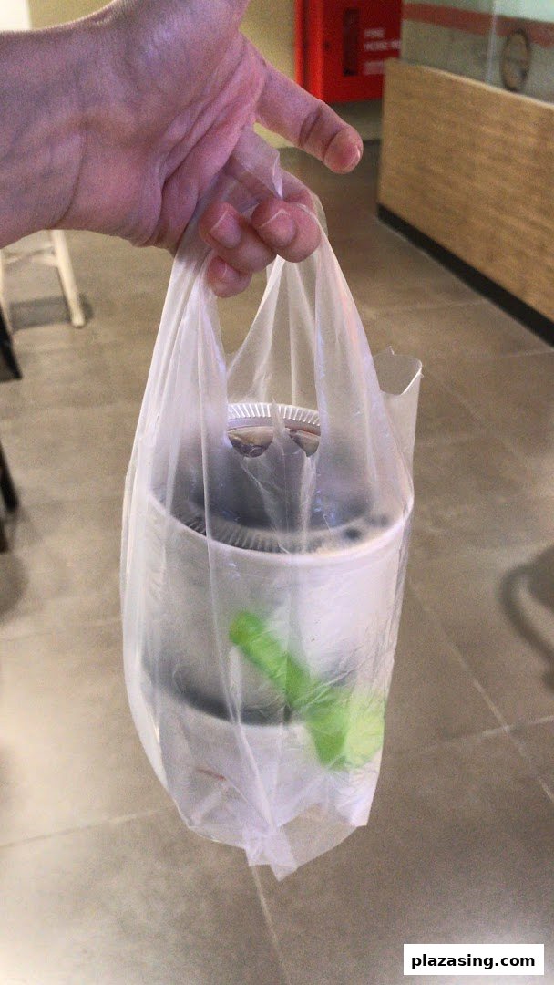 A hand holds a plastic bag containing a takeaway dessert from Nine Fresh.