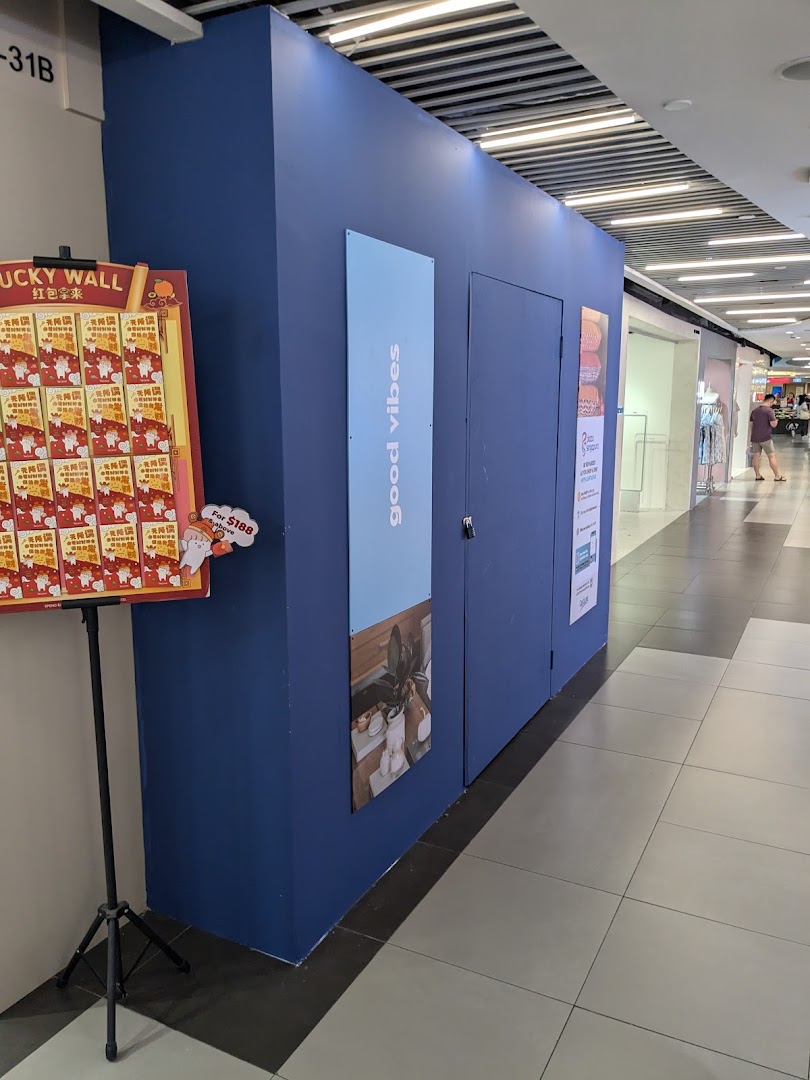 A temporary blue hoarding in a mall corridor, featuring a 'Lucky Wall' display and 'good vibes' signage.