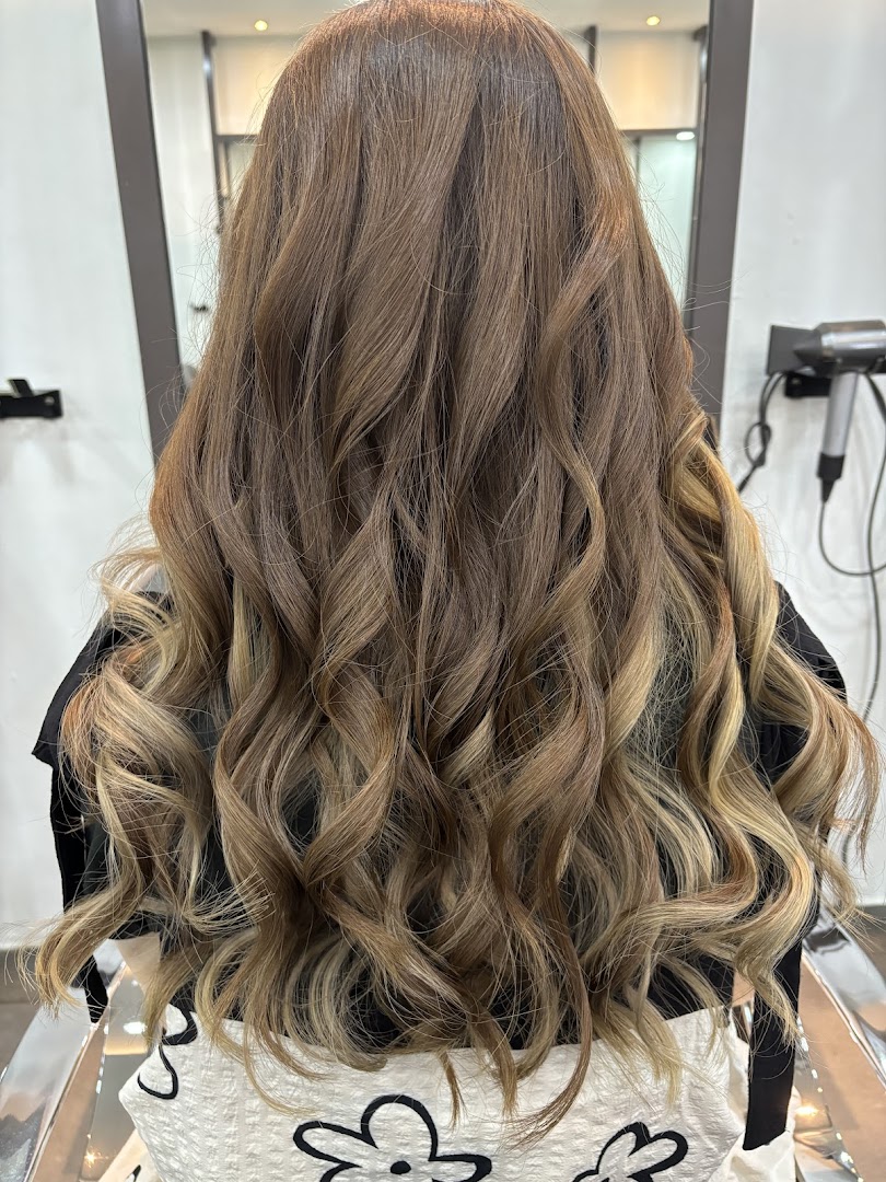 Back view of a client showcasing beautifully styled, wavy hair with highlights at NK Hairworks.