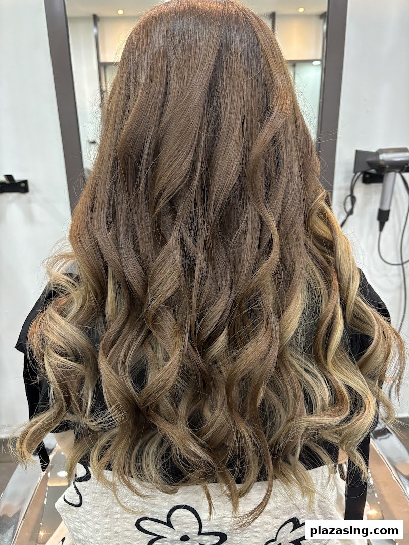 Back view of a client showcasing beautifully styled, wavy hair with highlights at NK Hairworks.