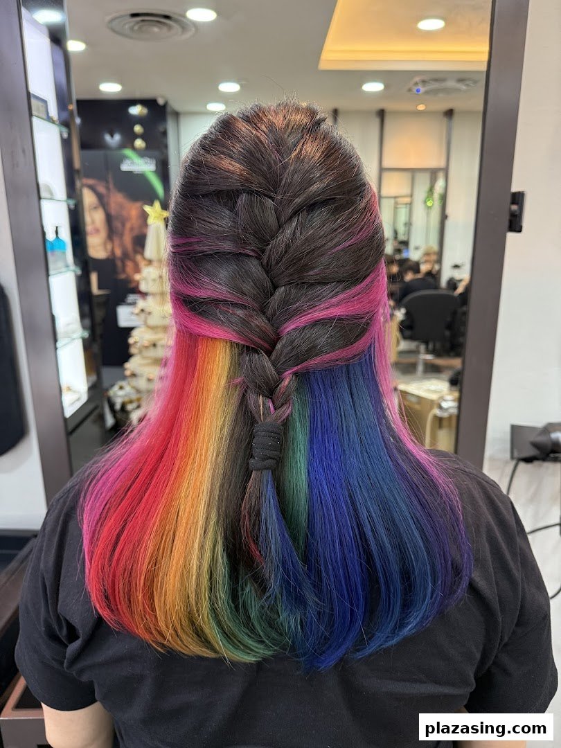 Rear view of a person with vibrant rainbow-colored hair styled in a half-braid at NK Hairworks.