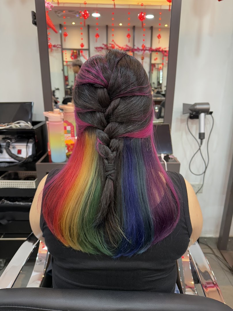 A client showcases vibrant rainbow and pink hair with a stylish braid at NK Hairworks.