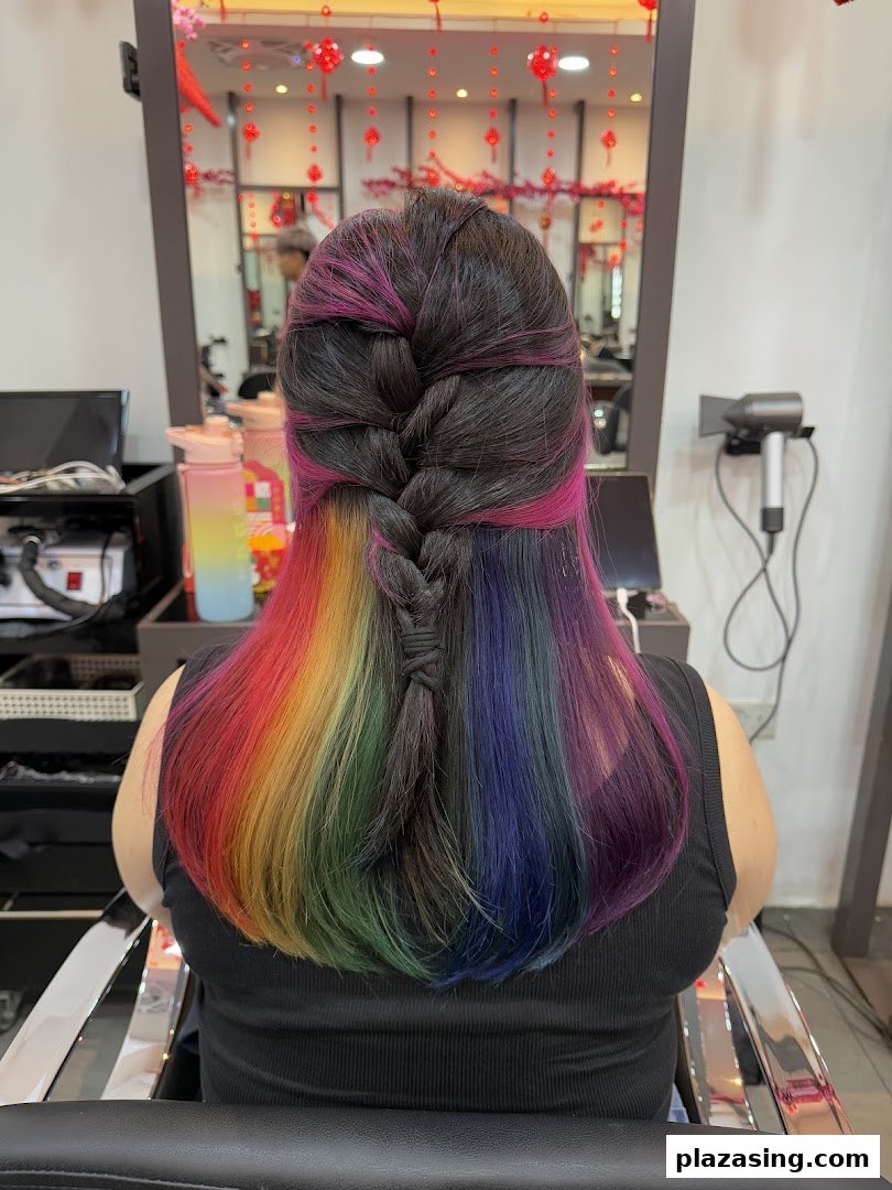 A client showcases vibrant rainbow and pink hair with a stylish braid at NK Hairworks.