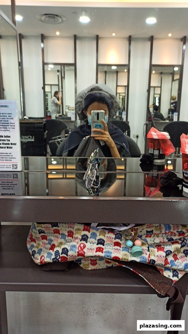 A customer wearing a hair cap and mask takes a mirror selfie inside NK Hairworks salon.