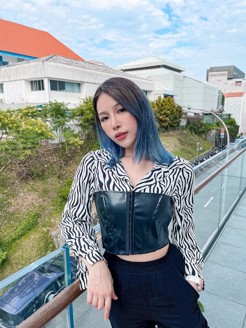 A person with vibrant blue hair poses outdoors, showcasing a stylish hair transformation.
