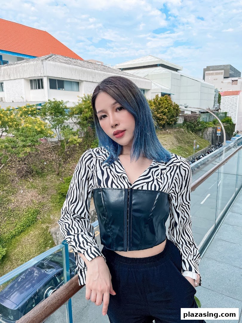 A person with vibrant blue hair poses outdoors, showcasing a stylish hair transformation.