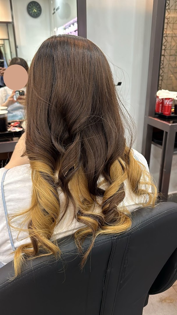 Rear view of a person showcasing brown hair with blonde highlights and styled curls in a salon.
