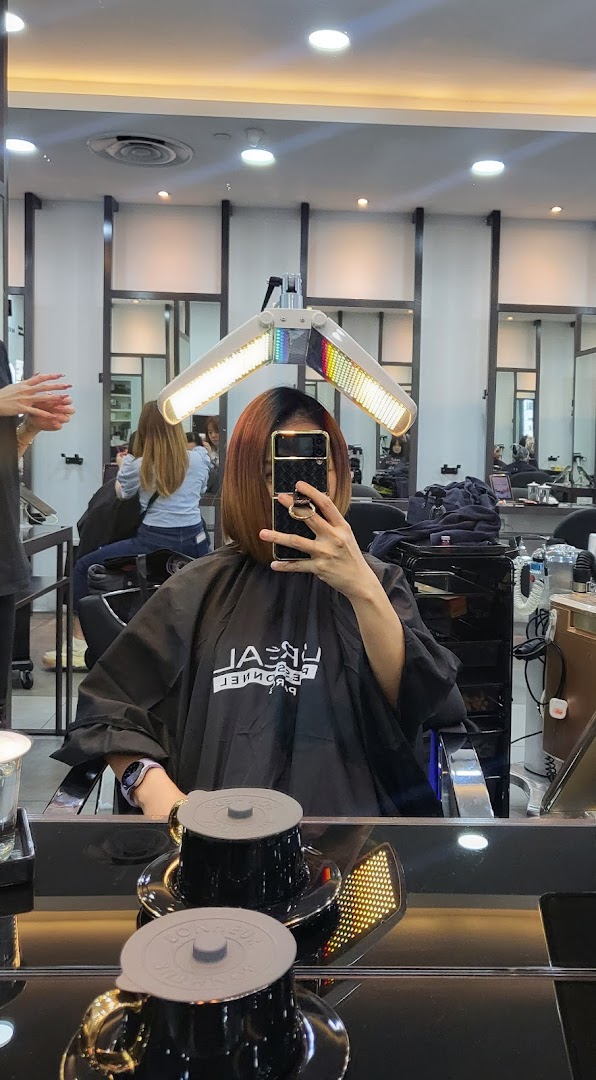 A customer receiving a hair treatment under a heat lamp at NK Hairworks salon.