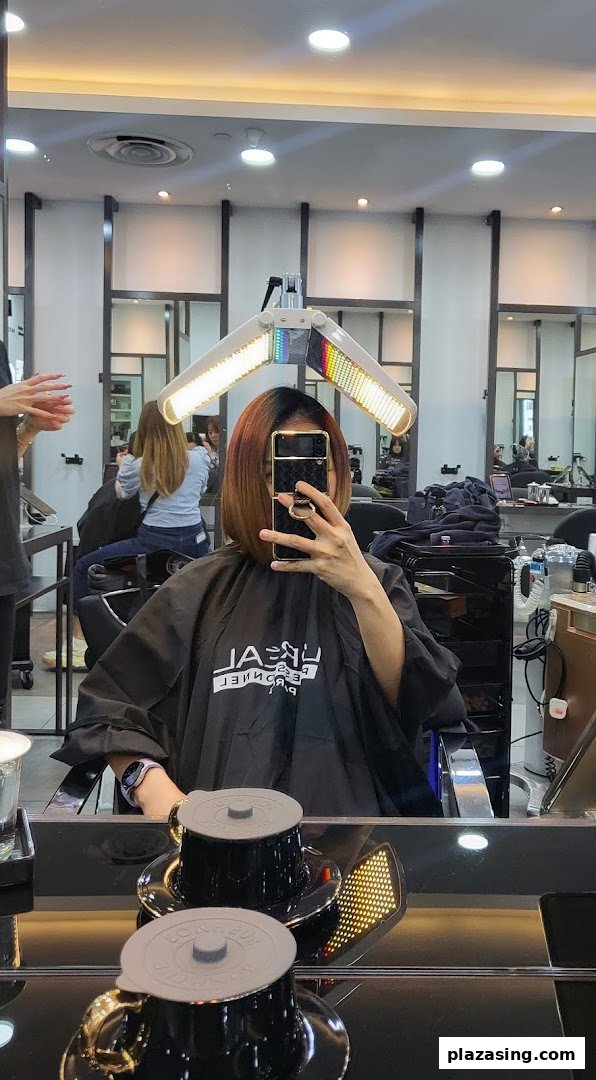 A customer receiving a hair treatment under a heat lamp at NK Hairworks salon.