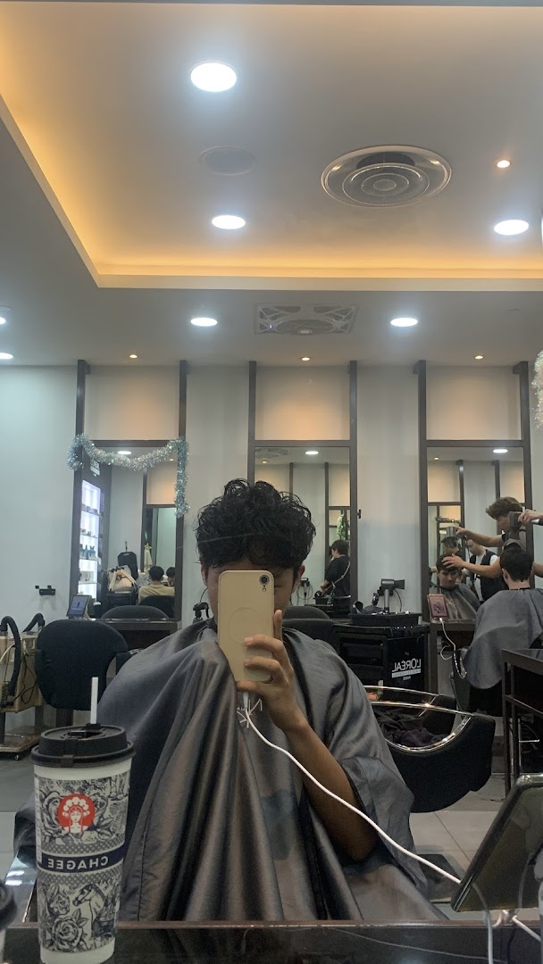 A customer taking a selfie in a hair salon, showcasing the modern interior and ongoing services.