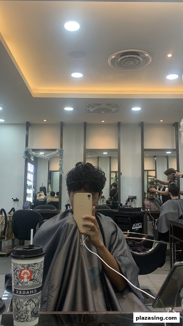 A customer taking a selfie in a hair salon, showcasing the modern interior and ongoing services.