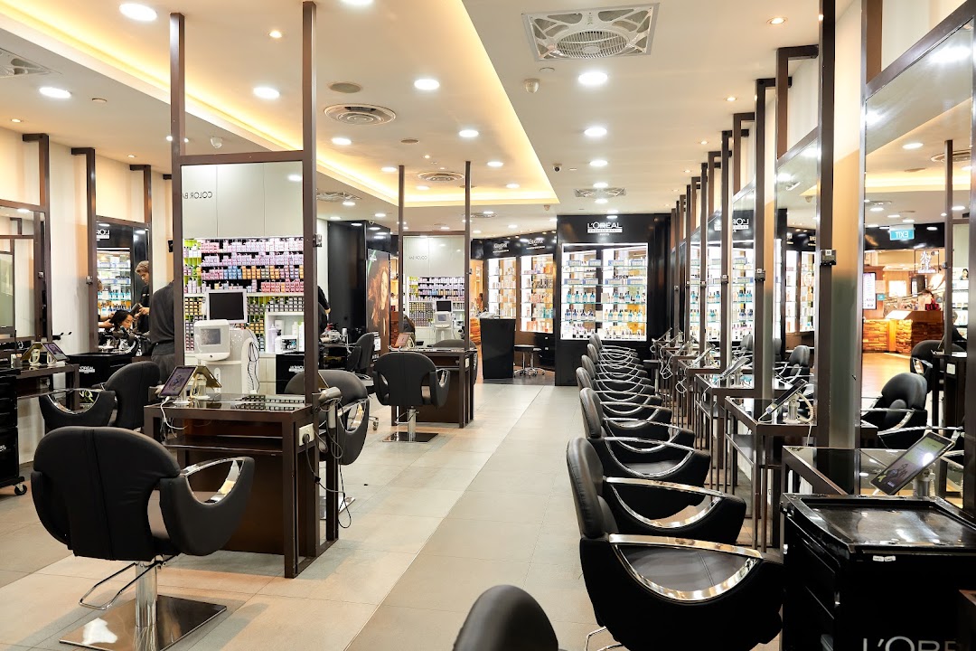 Interior view of a modern hair salon with multiple styling stations, mirrors, and product displays.