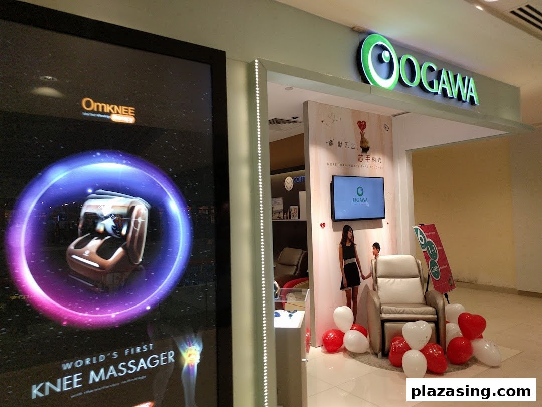 The OGAWA shop front features its bright green logo, a digital display for OmKNEE massager, and a massage chair setup.