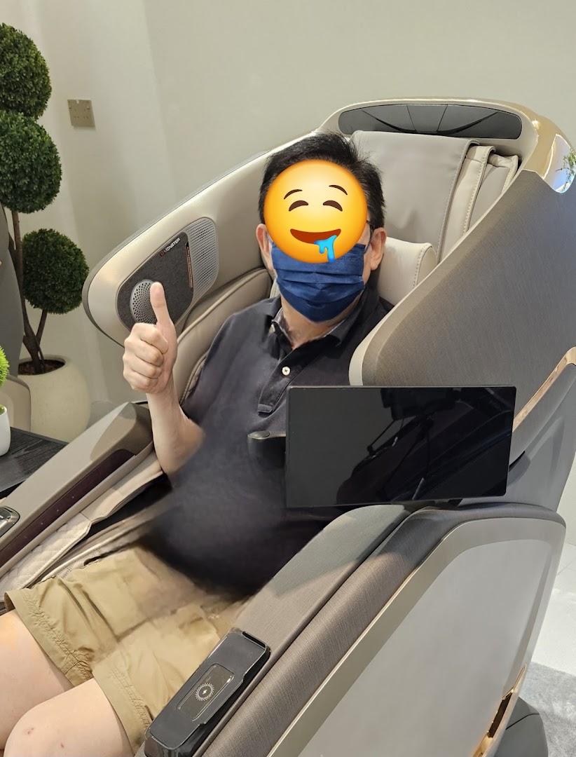 A man comfortably seated in a modern OGAWA massage chair, giving a thumbs-up.