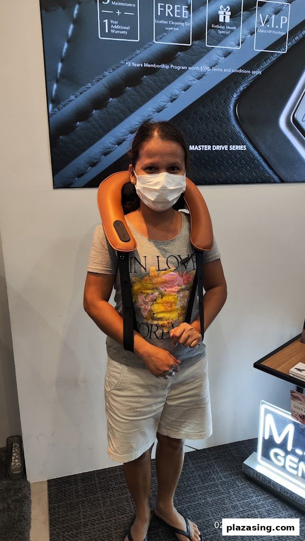 A customer trying a neck massager inside OGAWA, with promotional offers visible.