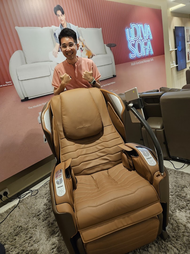 A person gives thumbs-up while seated in a brown OSIM massage chair, with a 'uDiva Sofa' poster behind.