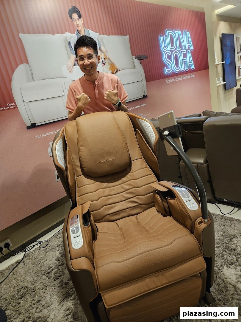 A person gives thumbs-up while seated in a brown OSIM massage chair, with a 'uDiva Sofa' poster behind.