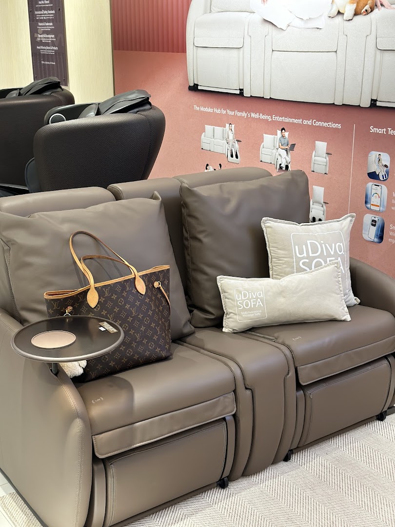An OSIM uDiva massage sofa displayed in a retail setting, featuring a luxury handbag.