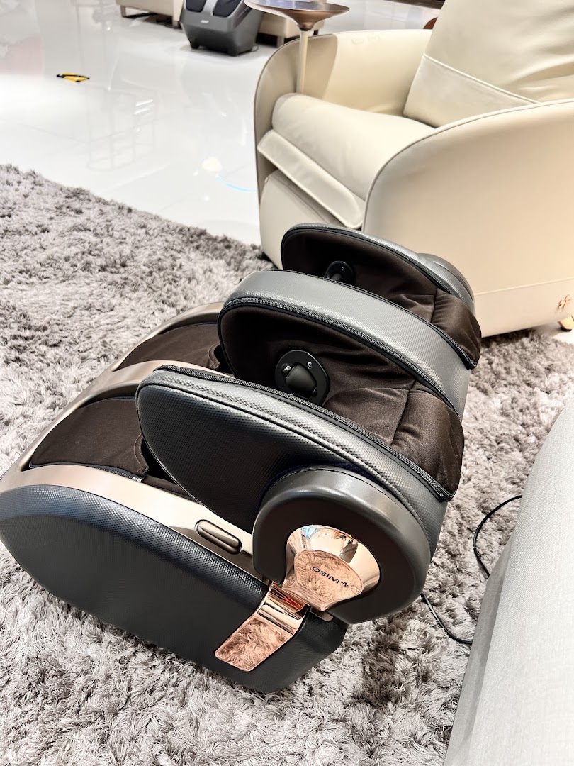 An OSIM foot massager on a grey rug, with a cream armchair in the background.