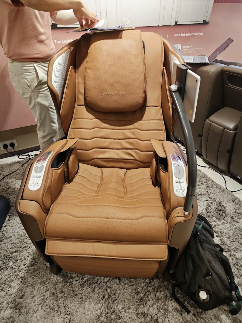 A luxurious brown massage chair with integrated technology on display in an OSIM store.