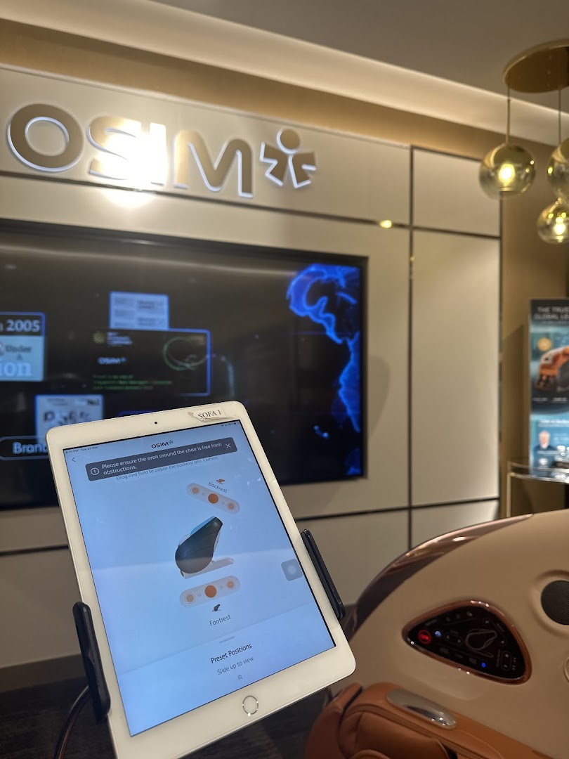 An OSIM massage chair with a control tablet displaying adjustment options in the store.