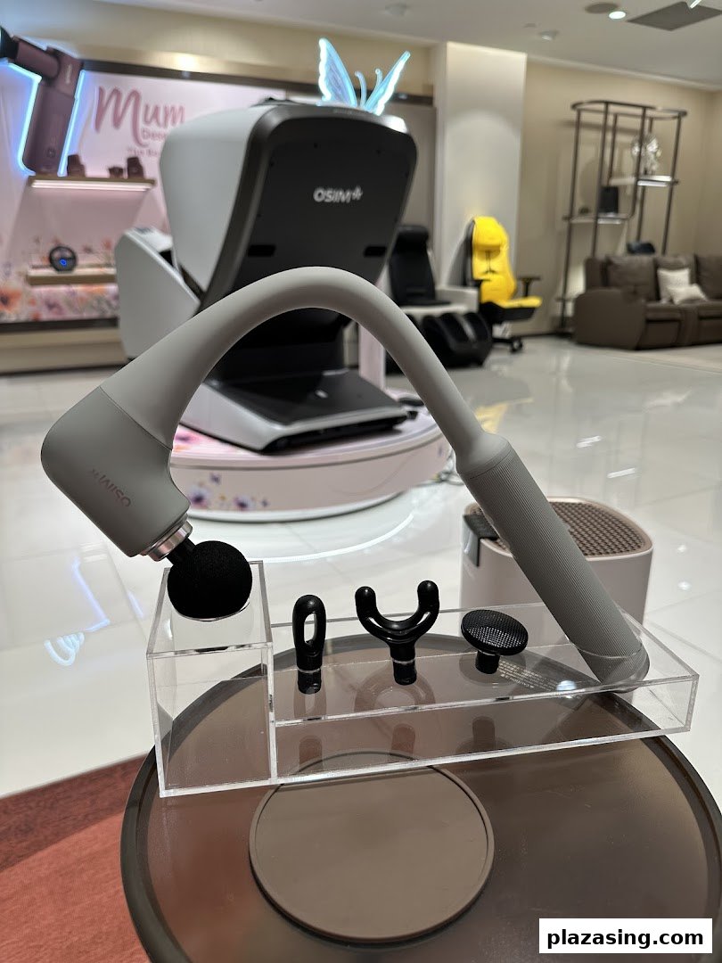 A massage gun with various attachments is displayed in the foreground, with OSIM massage chairs visible behind.