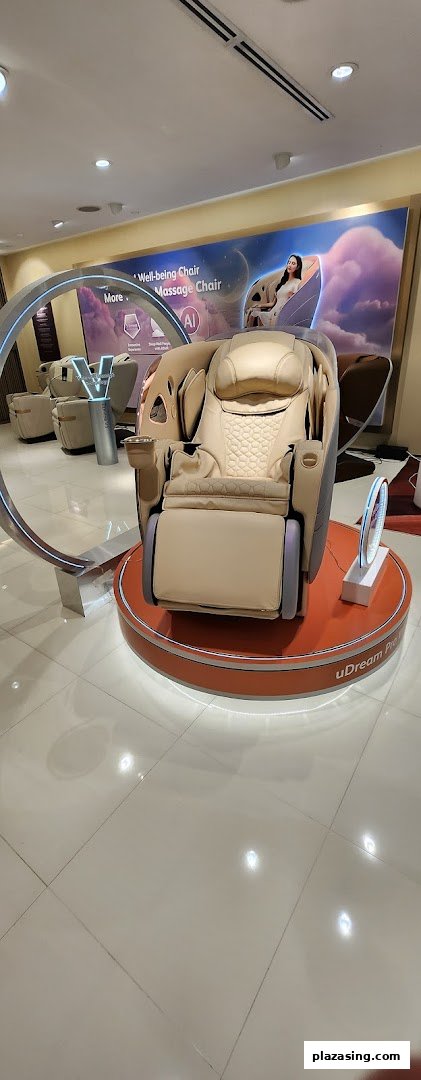 A modern beige massage chair displayed on a circular platform inside an OSIM store.