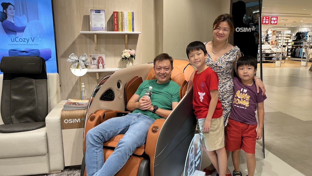 A family enjoys trying out massage chairs and wellness products inside an OSIM store.