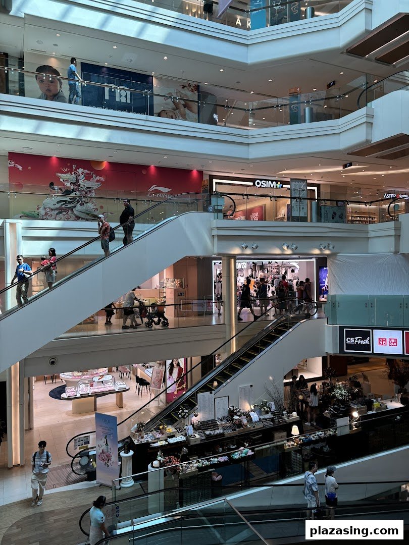 A bustling multi-level shopping mall interior with escalators and various retail stores, including OSIM.