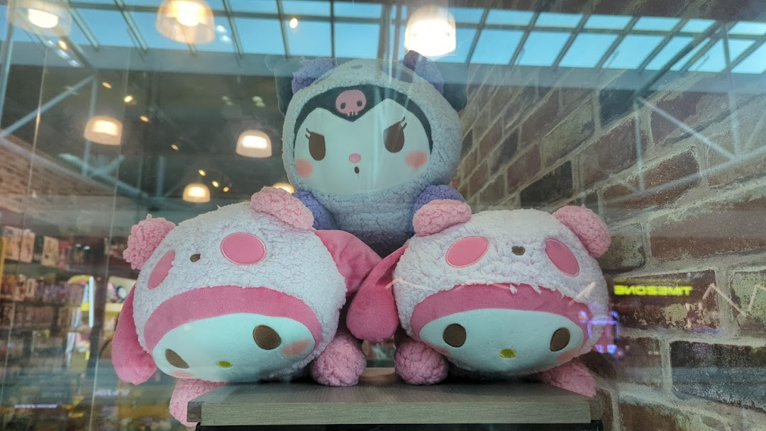Three large plush toys, including a Kuromi and two pink pig-like characters, displayed in a shop window.
