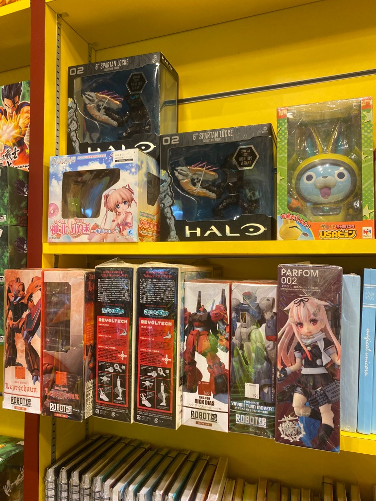 Shelves displaying a variety of anime figures, robot models, and collectible toys at Otaku House.