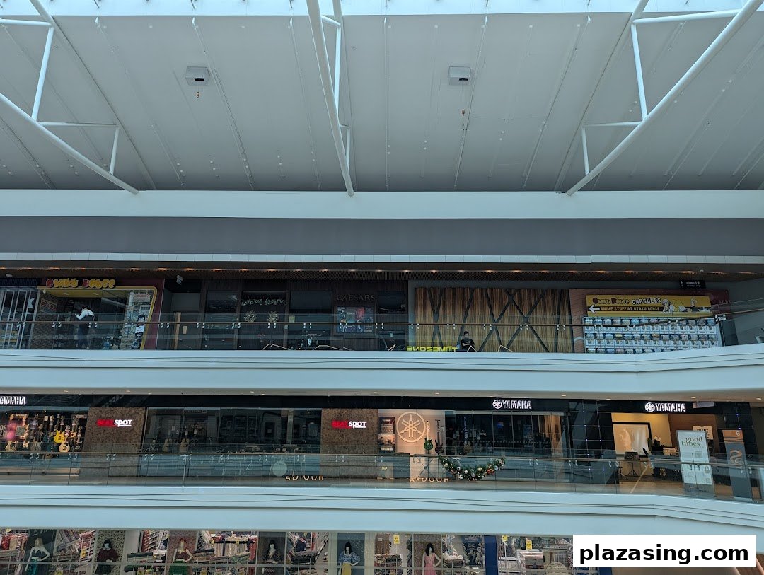 View of Otaku House and other shops on upper levels of Plaza Singapura mall, featuring anime gacha capsules.