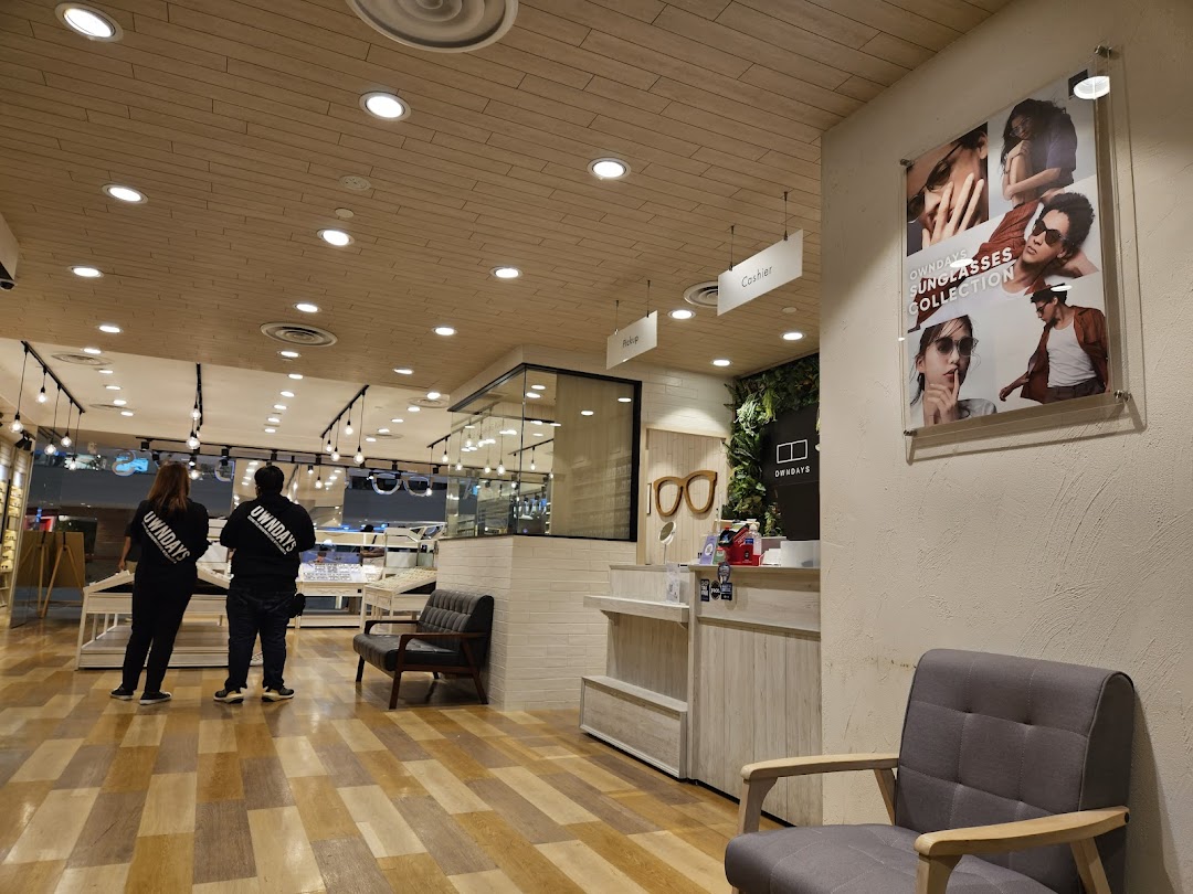 Interior view of OWNDAYS eyewear shop with staff, display cases, and a sunglasses collection poster.