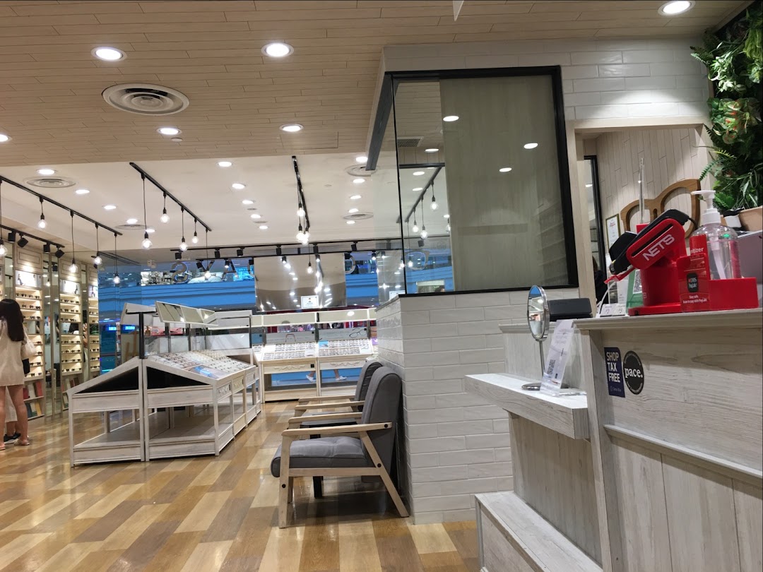 Interior view of OWNDAYS eyewear shop, showcasing display racks with glasses and a customer browsing.