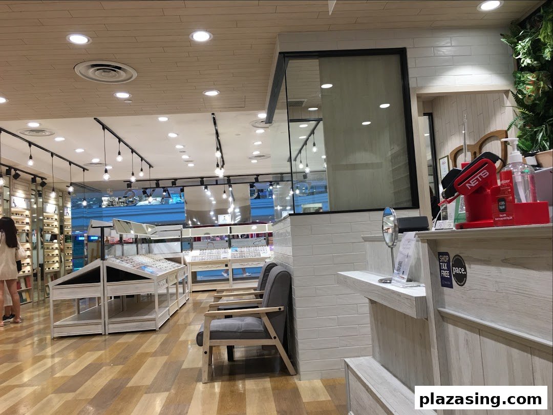 Interior view of OWNDAYS eyewear shop, showcasing display racks with glasses and a customer browsing.