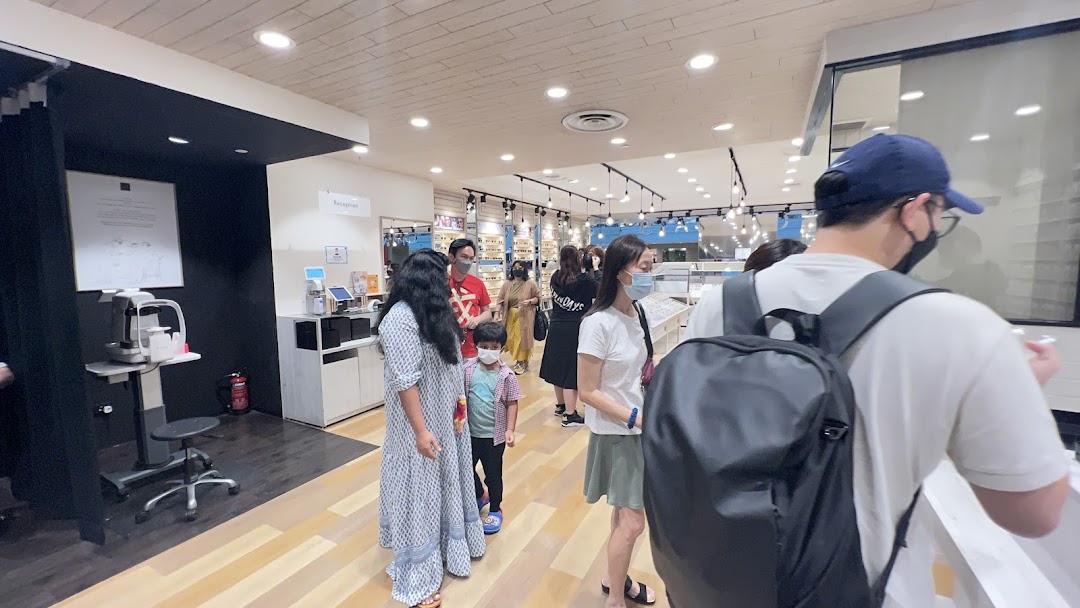 Customers browse and queue inside OWNDAYS, an optical shop featuring eyewear displays and eye examination equipment.