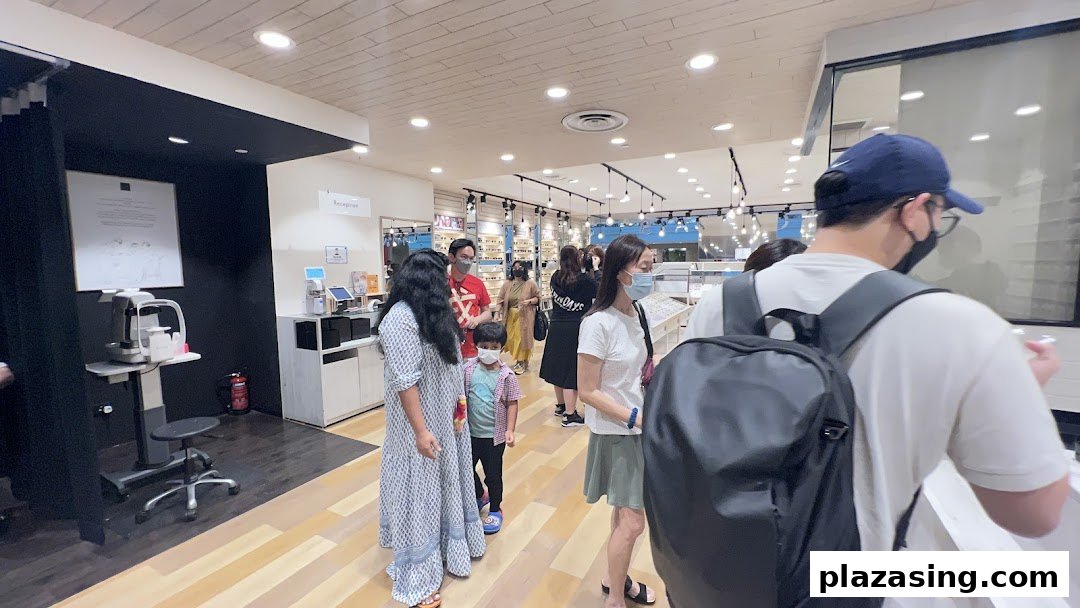 Customers browse and queue inside OWNDAYS, an optical shop featuring eyewear displays and eye examination equipment.