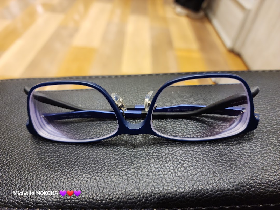 A pair of stylish blue-framed eyeglasses with clear lenses rests on a textured black surface.