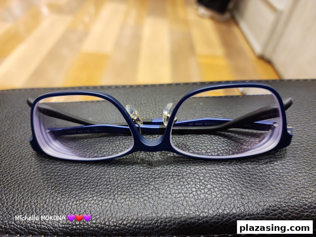 A pair of stylish blue-framed eyeglasses with clear lenses rests on a textured black surface.