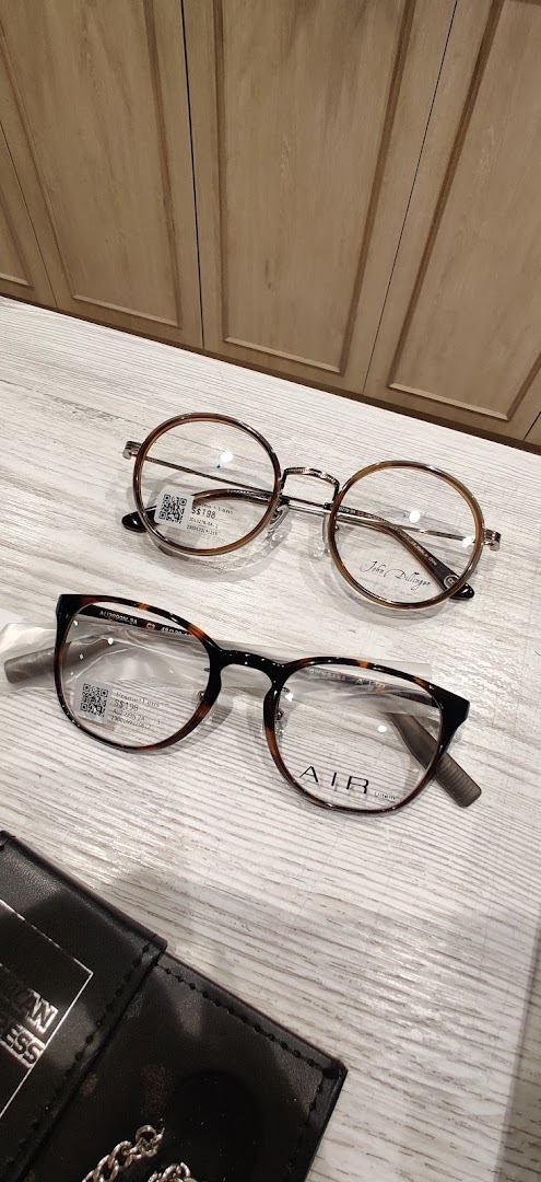 Two pairs of stylish eyeglasses, one round and one rectangular, displayed on a light wooden surface.