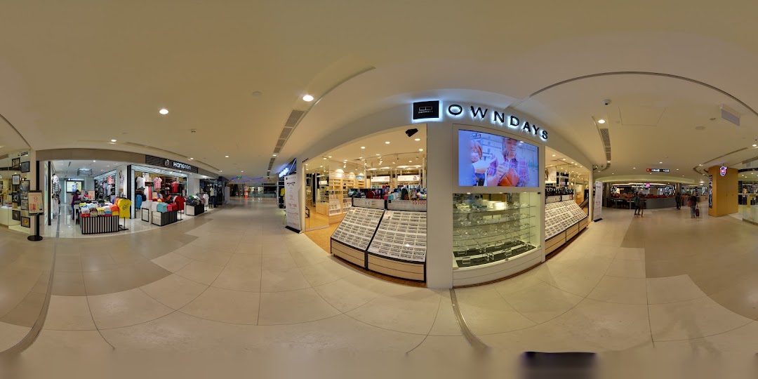 The bright and inviting storefront of OWNDAYS, an eyewear shop, within a bustling shopping mall.